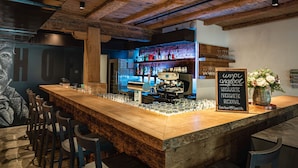 Un espace bar avec un comptoir en bois, des tabourets et un panneau d’affichage noir.