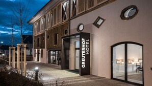 L’extérieur de l’hôtel Greuterhof se distingue par sa façade moderne, ses grandes portes vitrées et son hall d’entrée bien éclairé.
