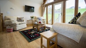 A cozy living room with two sofas, a coffee table, and a TV mounted on the wall. - Tynrhyd Retreat (Aberystwyth)