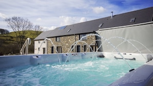 A hot tub with water jets, a stone building with a sloped roof, and a clear sky. - Tynrhyd Retreat (Aberystwyth)