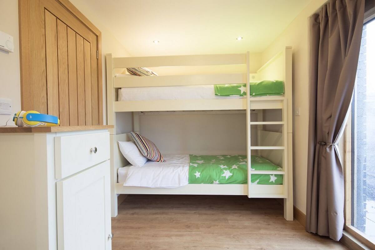 Une chambre avec un lit superposé, une armoire en bois et une fenêtre avec des rideaux.