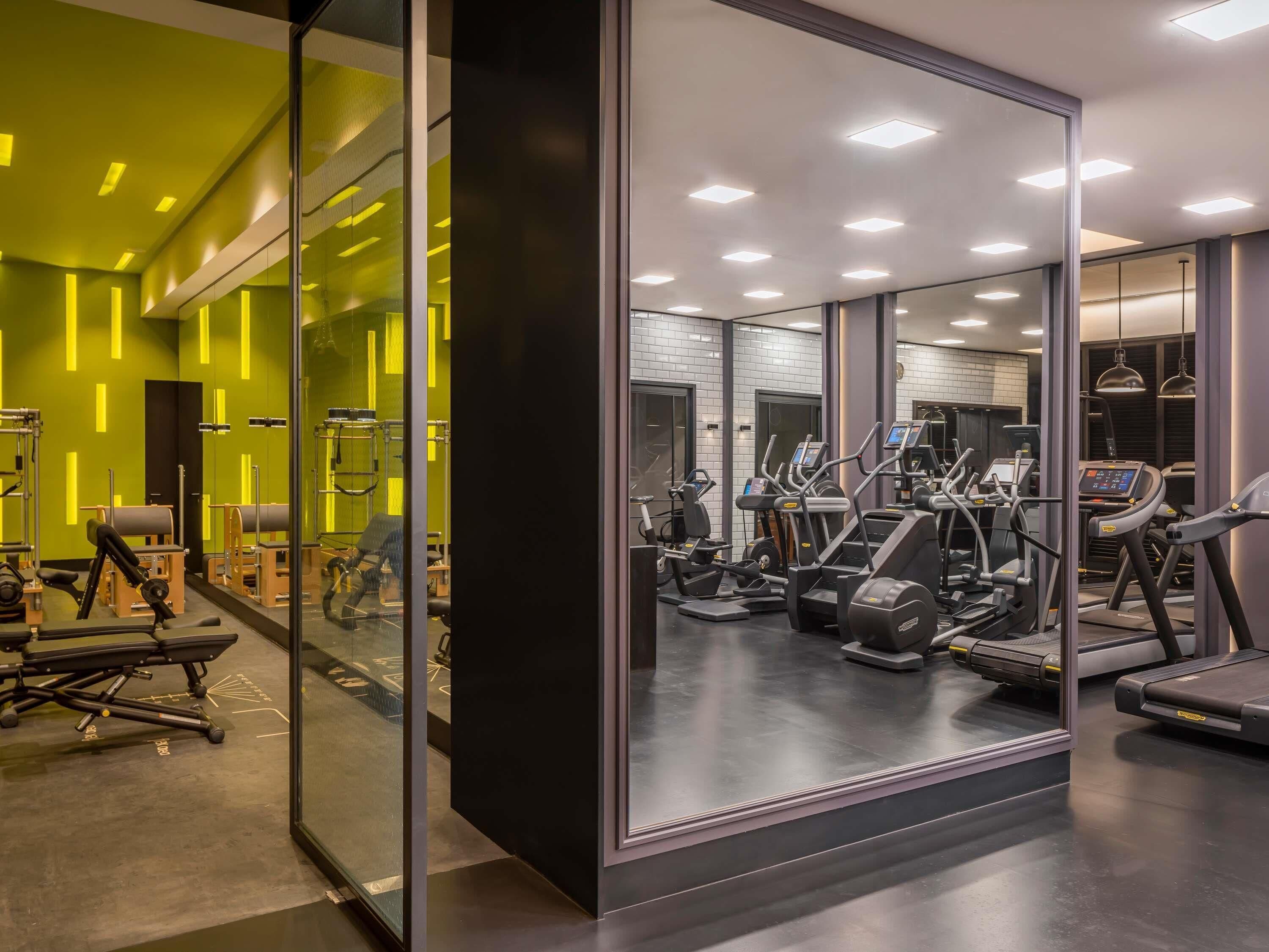 A modern gym with exercise equipment, glass walls, and bright lighting.
