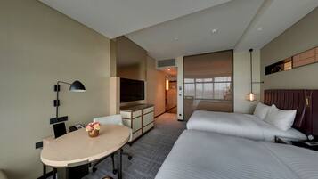 A hotel room with a bed, a desk, a TV, and a window.