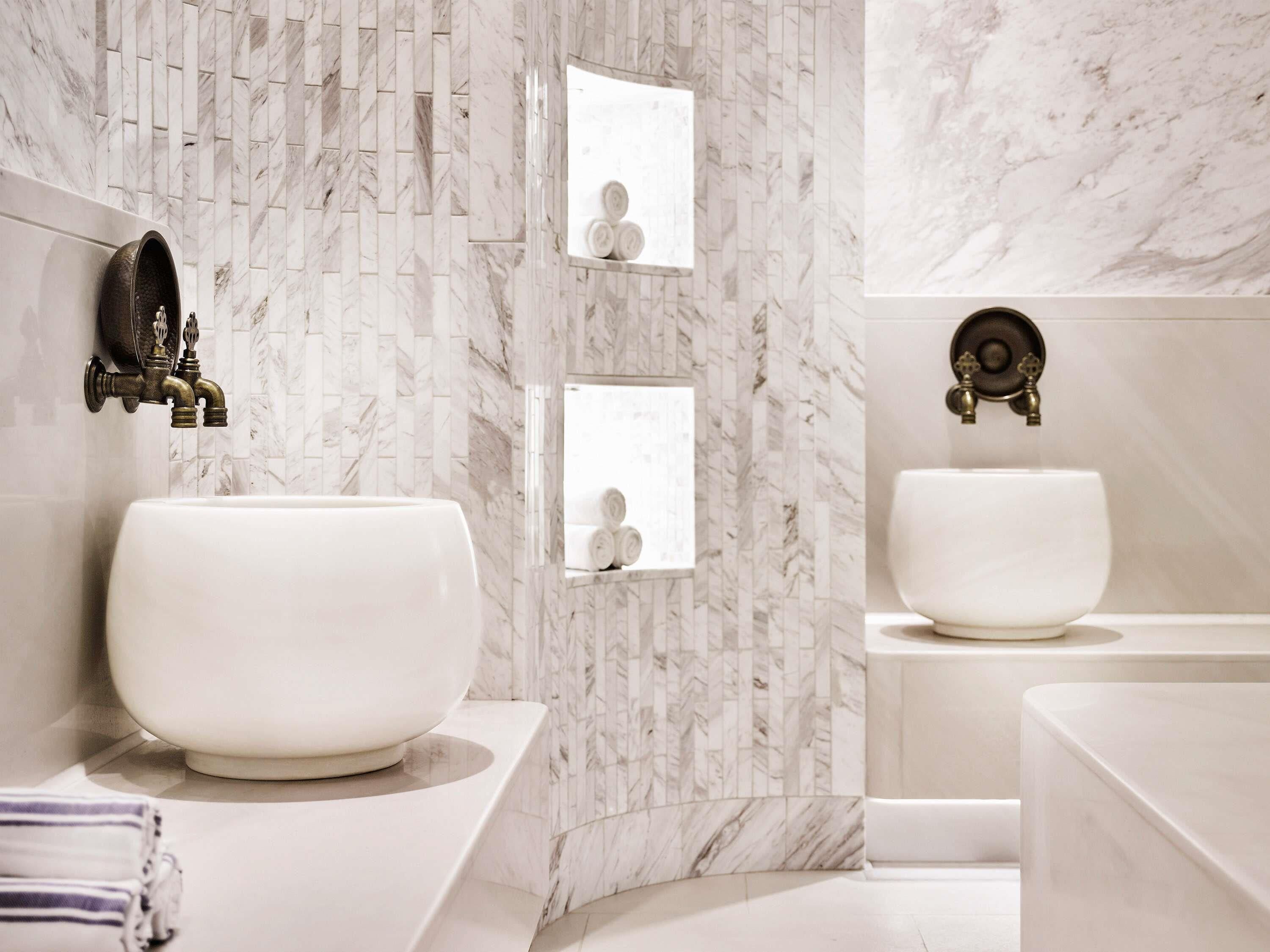 A bathroom with two sinks, marble walls, and a mirror.