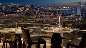 A rooftop dining area with tables and chairs, overlooking a cityscape at dusk. - Fairmont Quasar Istanbul (Istanbul)