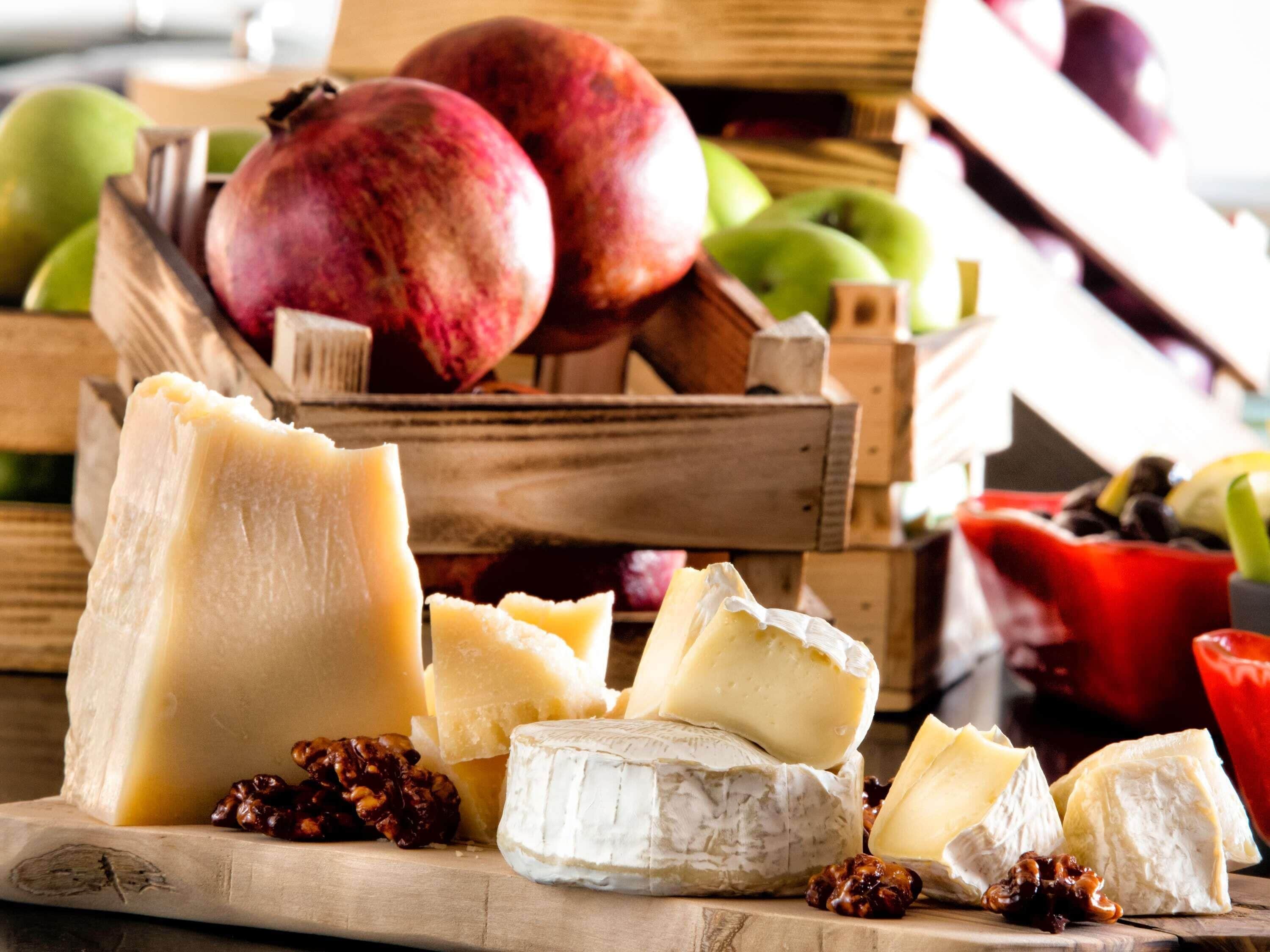 A variety of cheeses and fruits on a wooden surface.