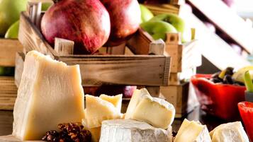 A variety of cheeses and fruits on a wooden surface.