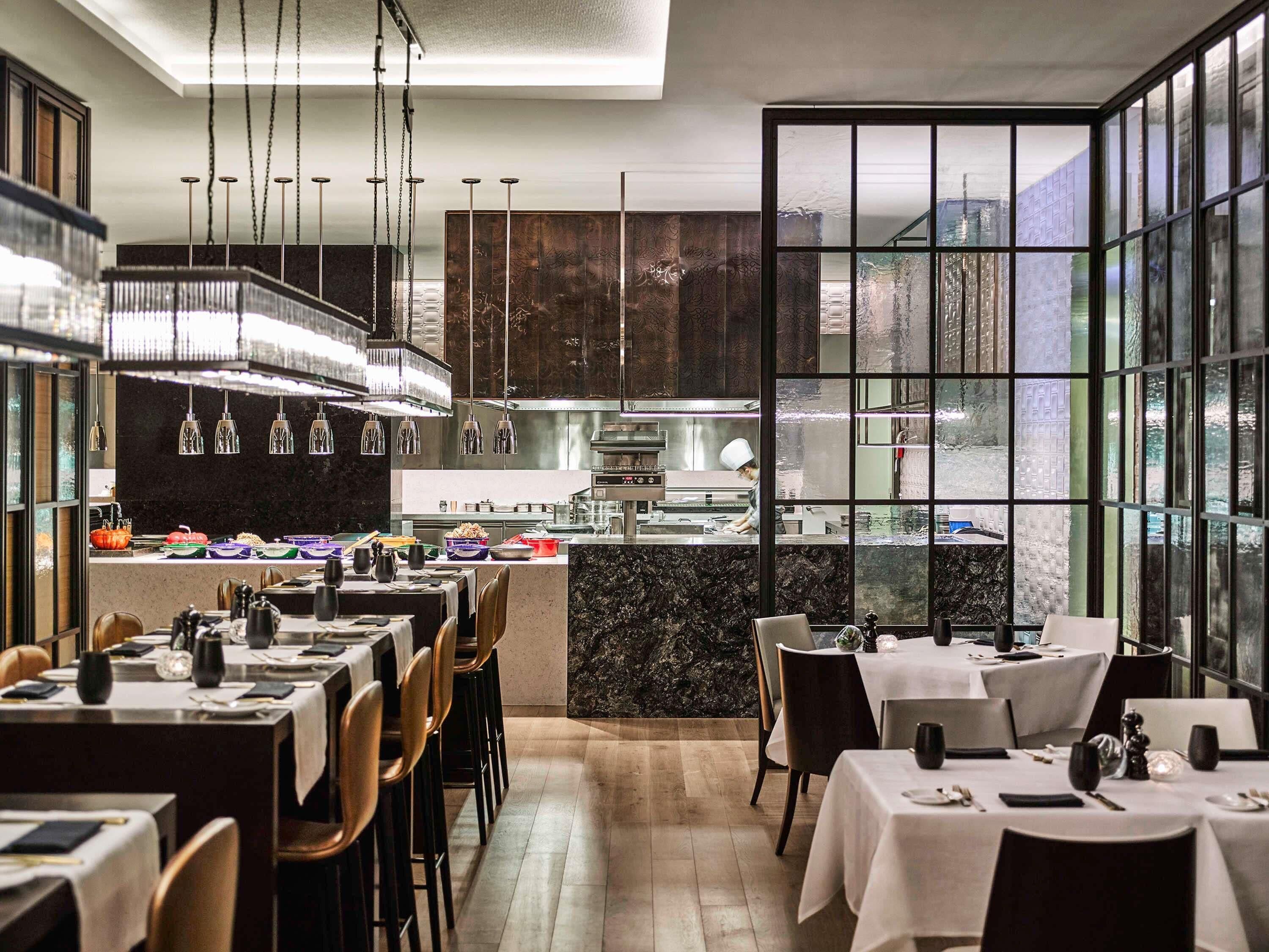 Un interno ristorante moderno con cucina centrale, tavoli e sedie.