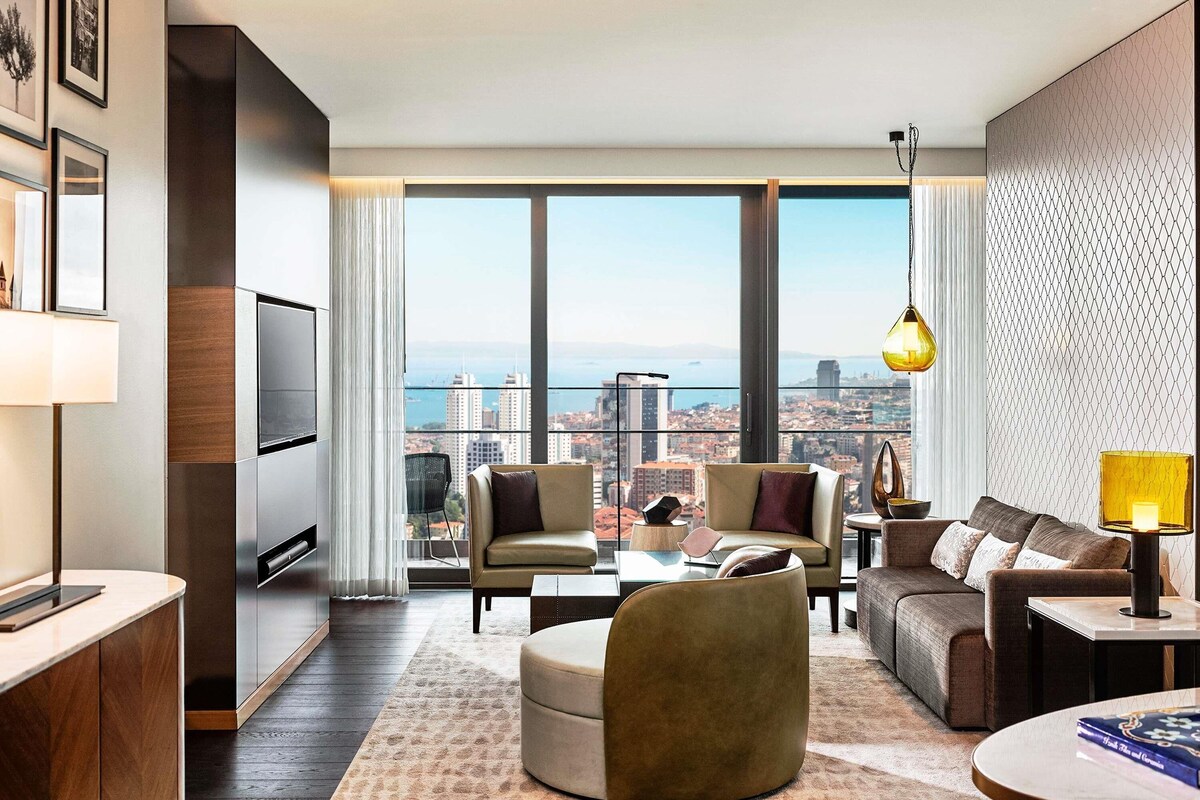 A modern living room with a city view, a sofa, a coffee table, and a TV.