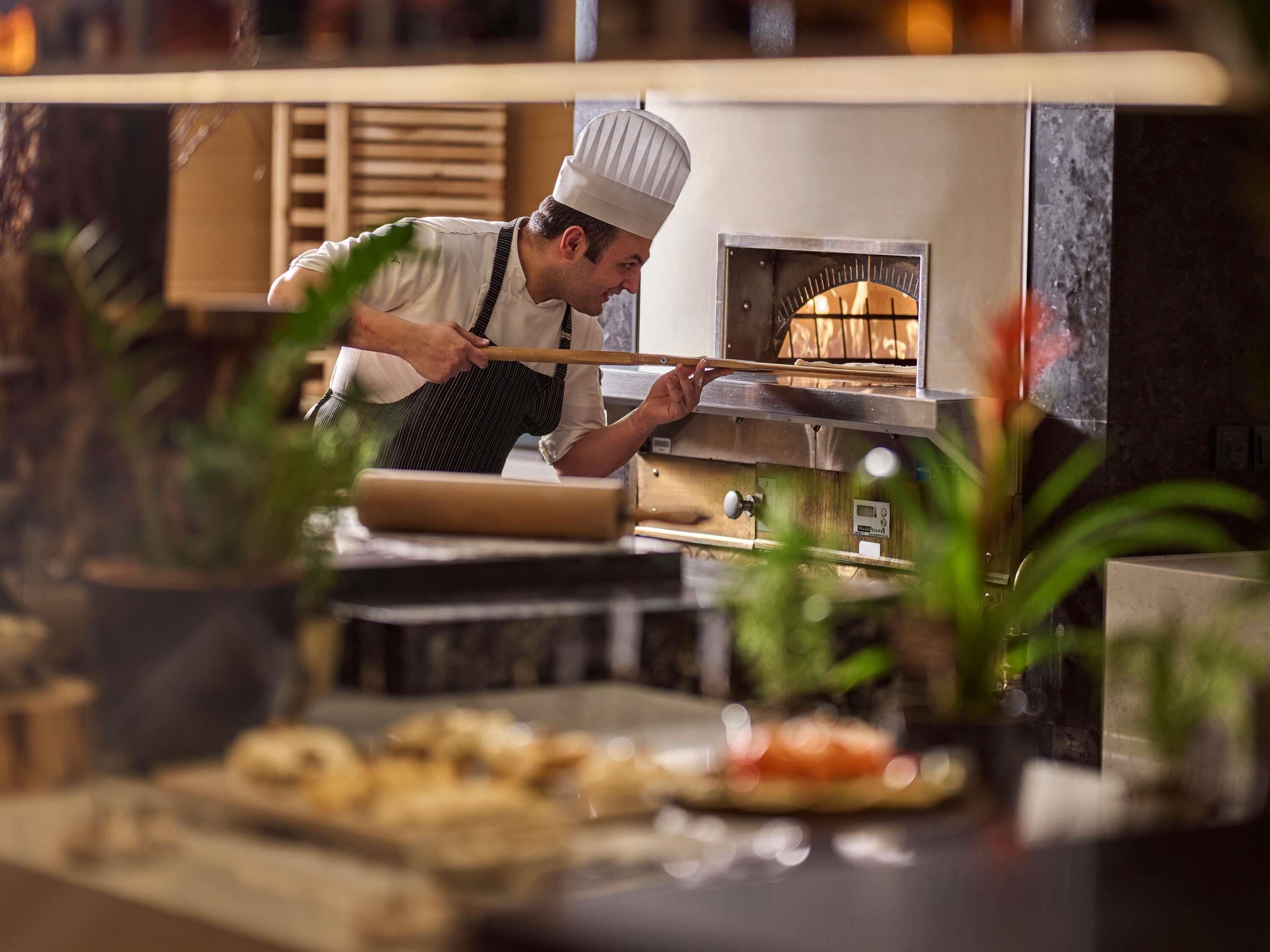 Un chef usando un rodillo en una cocina con horno de leña.