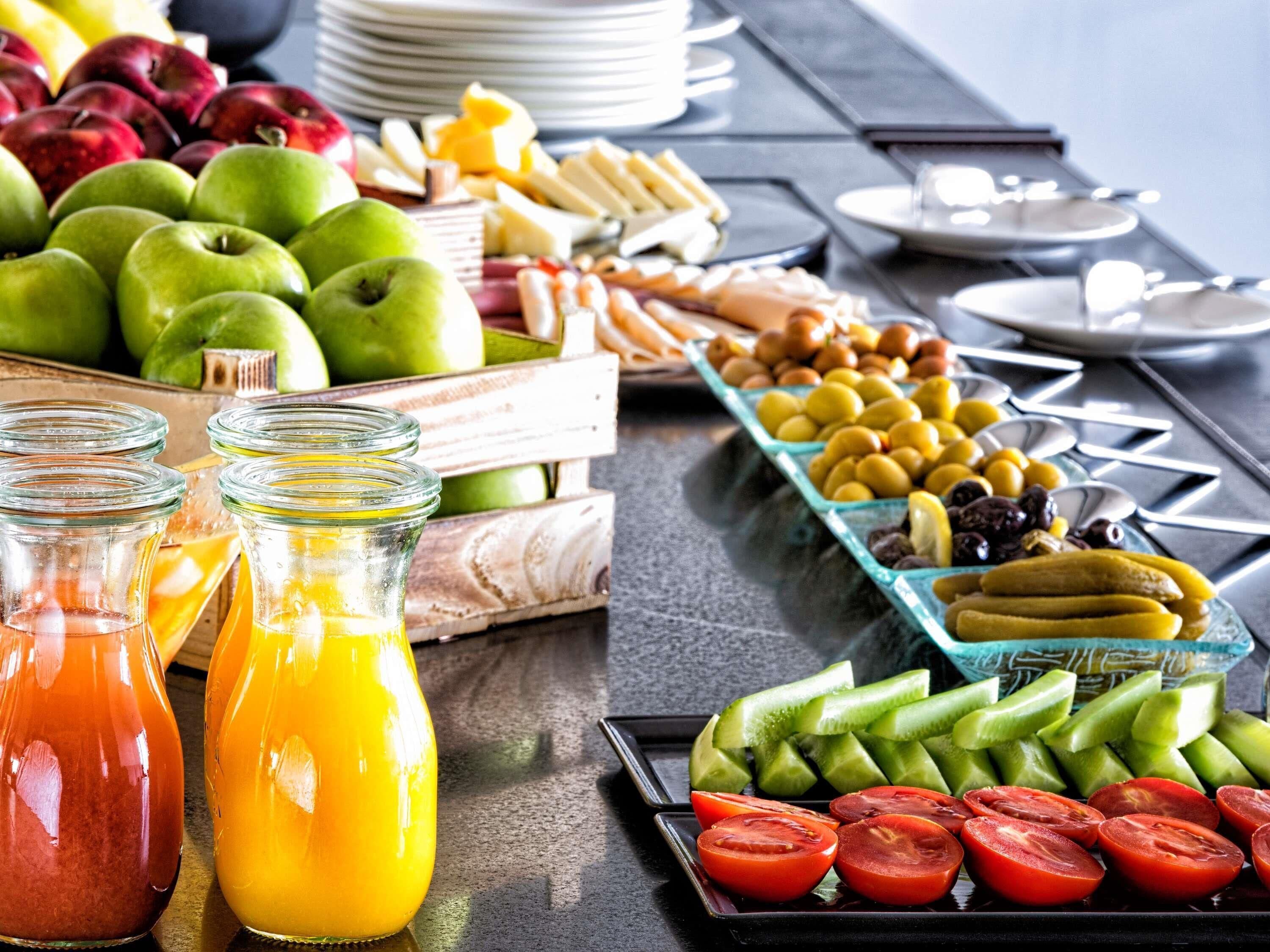 A buffet table with various fruits, vegetables, and condiments.