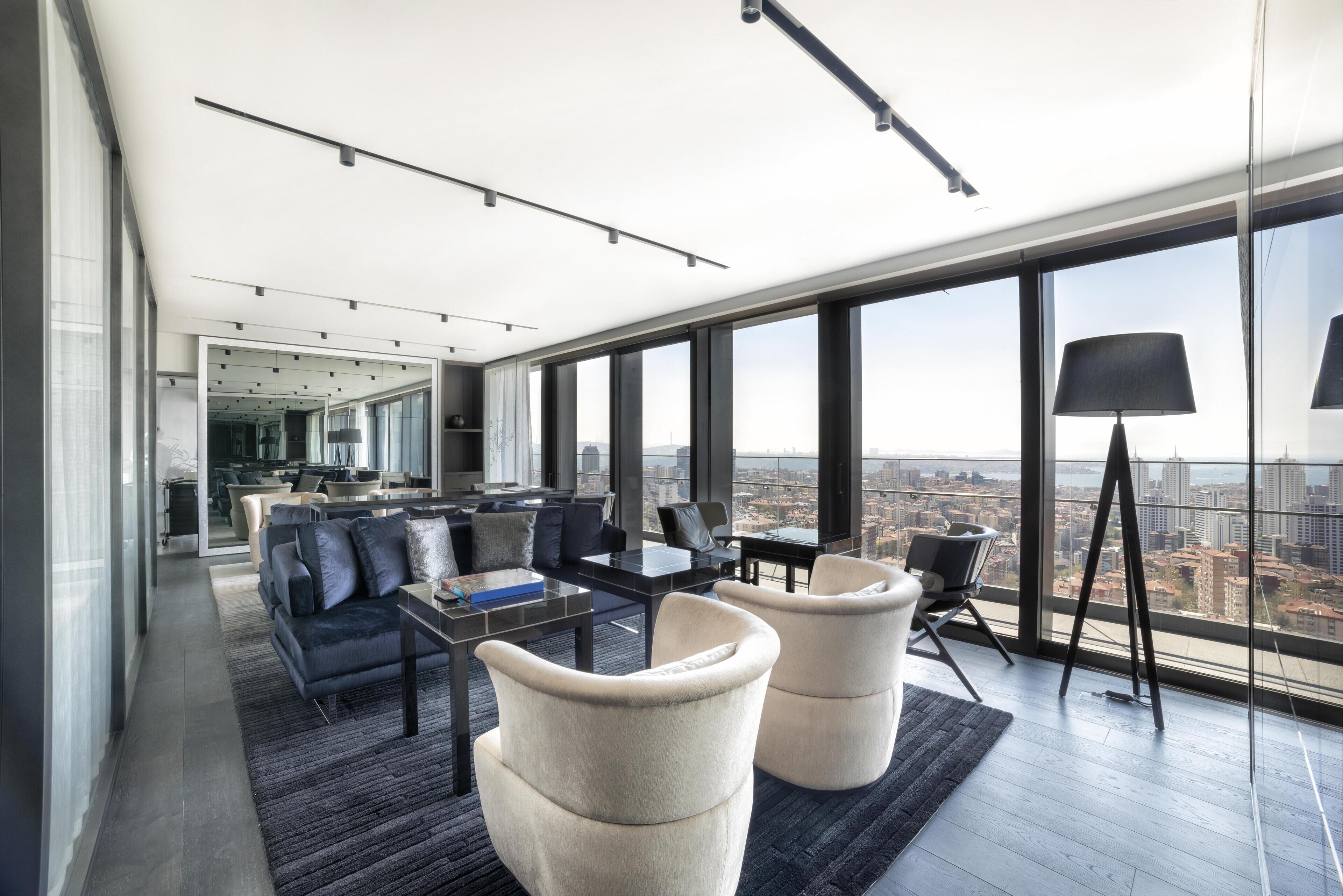 Una sala de estar moderna con un sofá, sillones, una mesa de centro y una lámpara.
