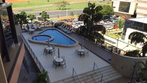 Zona de piscina en la azotea con sillones de descanso y mesas, rodeada de escalones y plantas en macetas.