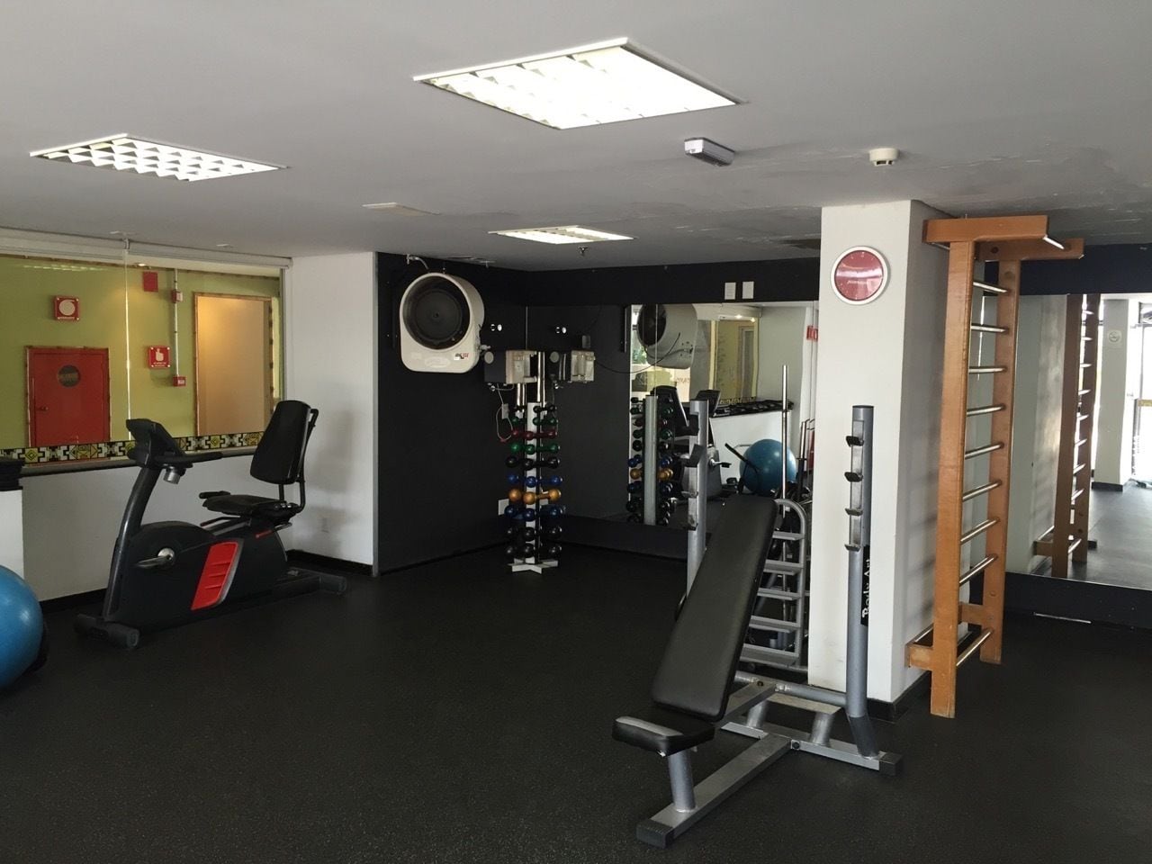 A gym with exercise equipment, a wall-mounted punching bag, and a pull-up bar.
