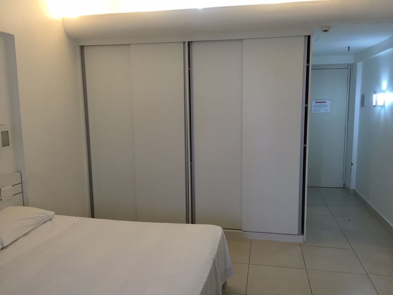 Een hotelkamer met een bed, een kast en een deur naar een andere kamer.