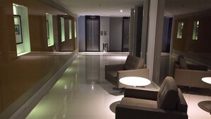 Un moderno vestíbulo de hotel con un largo pasillo, zonas de estar y ascensores.