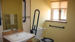 Une salle de bain avec un lavabo blanc, des toilettes et une fenêtre avec un cadre en bois.