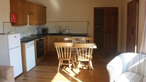 Une cuisine compacte dotée de meubles en bois, d’un réfrigérateur, d’un four à micro-ondes et d’un coin repas avec des chaises en bois.