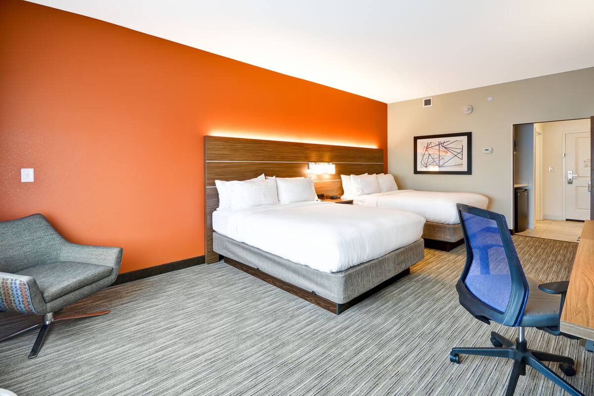 Ein Hotelzimmer mit zwei Betten, einem Schreibtisch, einem Stuhl und Teppichboden.