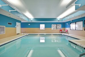 An indoor swimming pool with clear water, safety signs, and a view of trees through the windows. - Holiday Inn Express Evansville by IHG (Evansville)