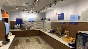 Un moderno comedor con mostrador, máquina de café y diferentes alimentos.