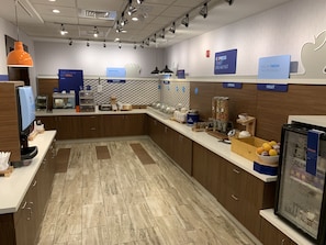 A modern breakfast area with a counter, coffee machine, and various food items. - Holiday Inn Express Evansville by IHG (Evansville)
