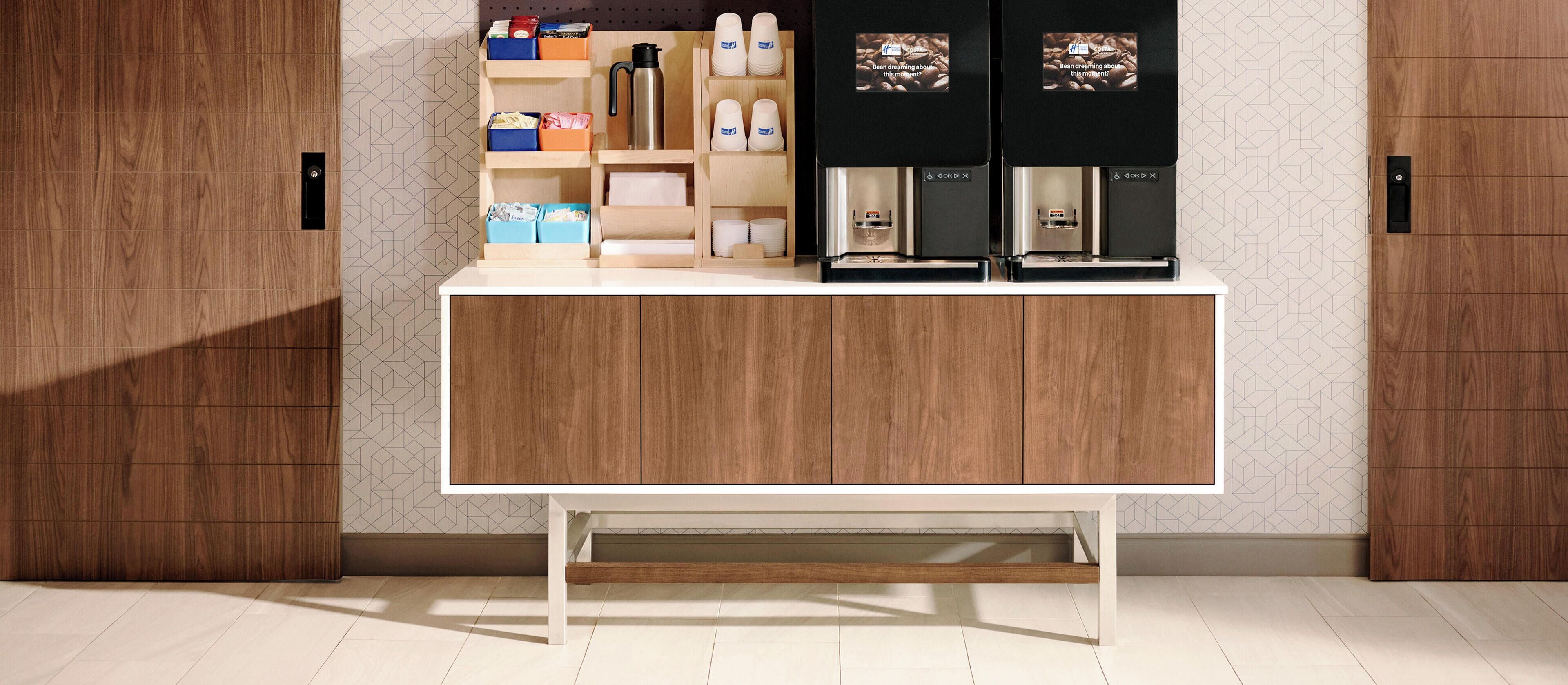 Una kitchenette moderna con un mueble de madera, una cafetera y estanterías.