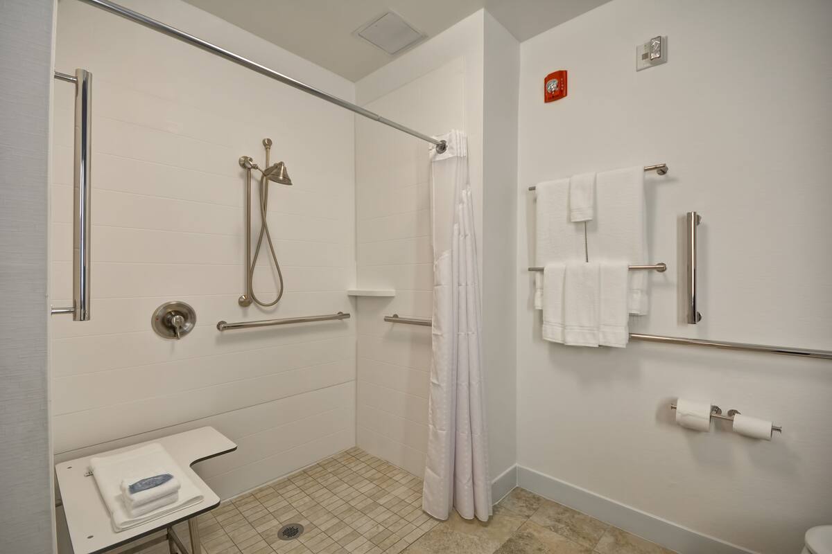 Ein modernes Badezimmer mit Dusche, Haltegriffen, Toilette und Waschbecken.