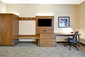 A hotel room with a wooden desk, a flat-screen TV, a chair, and a cabinet.
