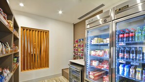 Una habitación de hotel con minibar, un refrigerador lleno de bebidas y un bar de aperitivos con diversos alimentos.