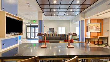A modern interior with a long communal table, seating, and a television.