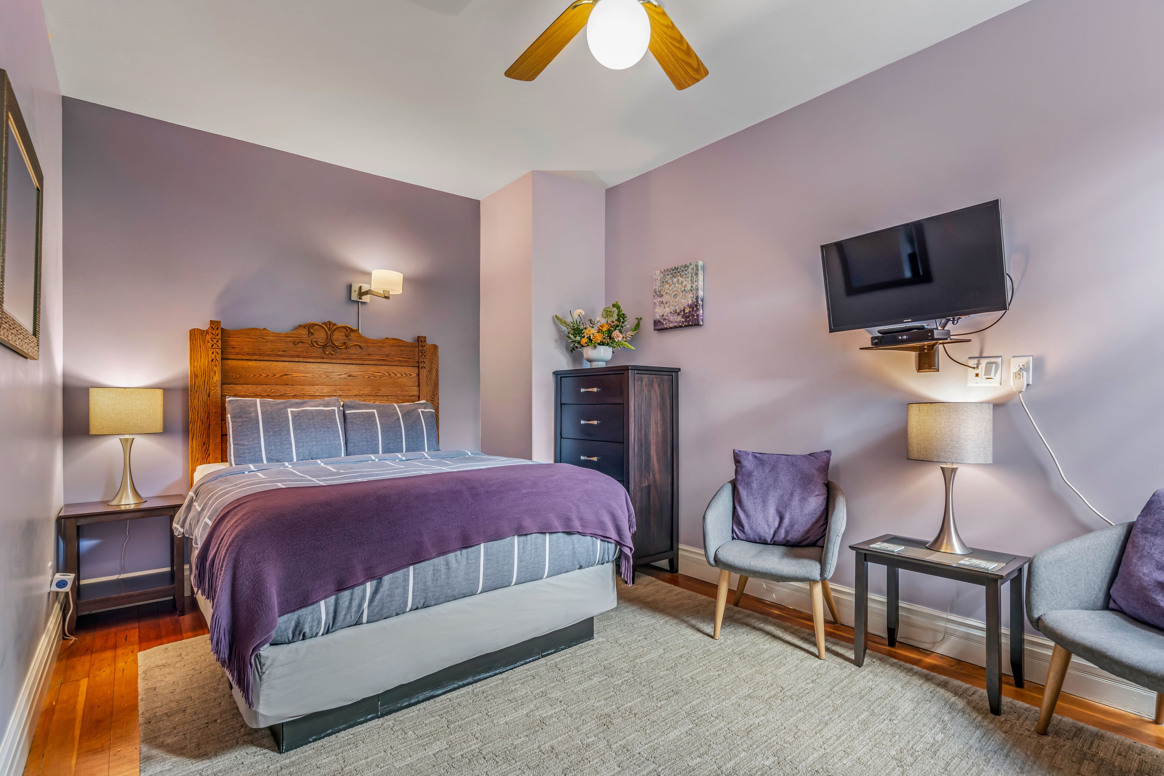 A bedroom with a bed, nightstands, a TV, and a chair.