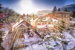 A snow-covered residential area with houses, a greenhouse, and a mountain backdrop. - Cloudside Hotel (Nelson)