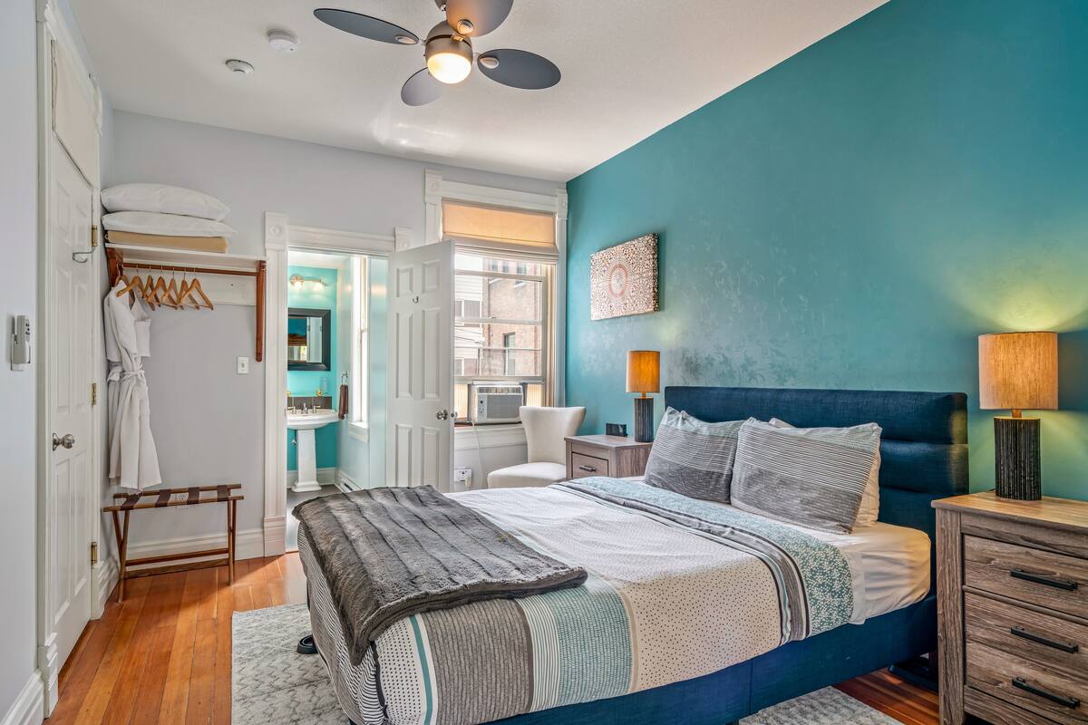 A bedroom with a bed, bedside tables, a ceiling fan, and a window.
