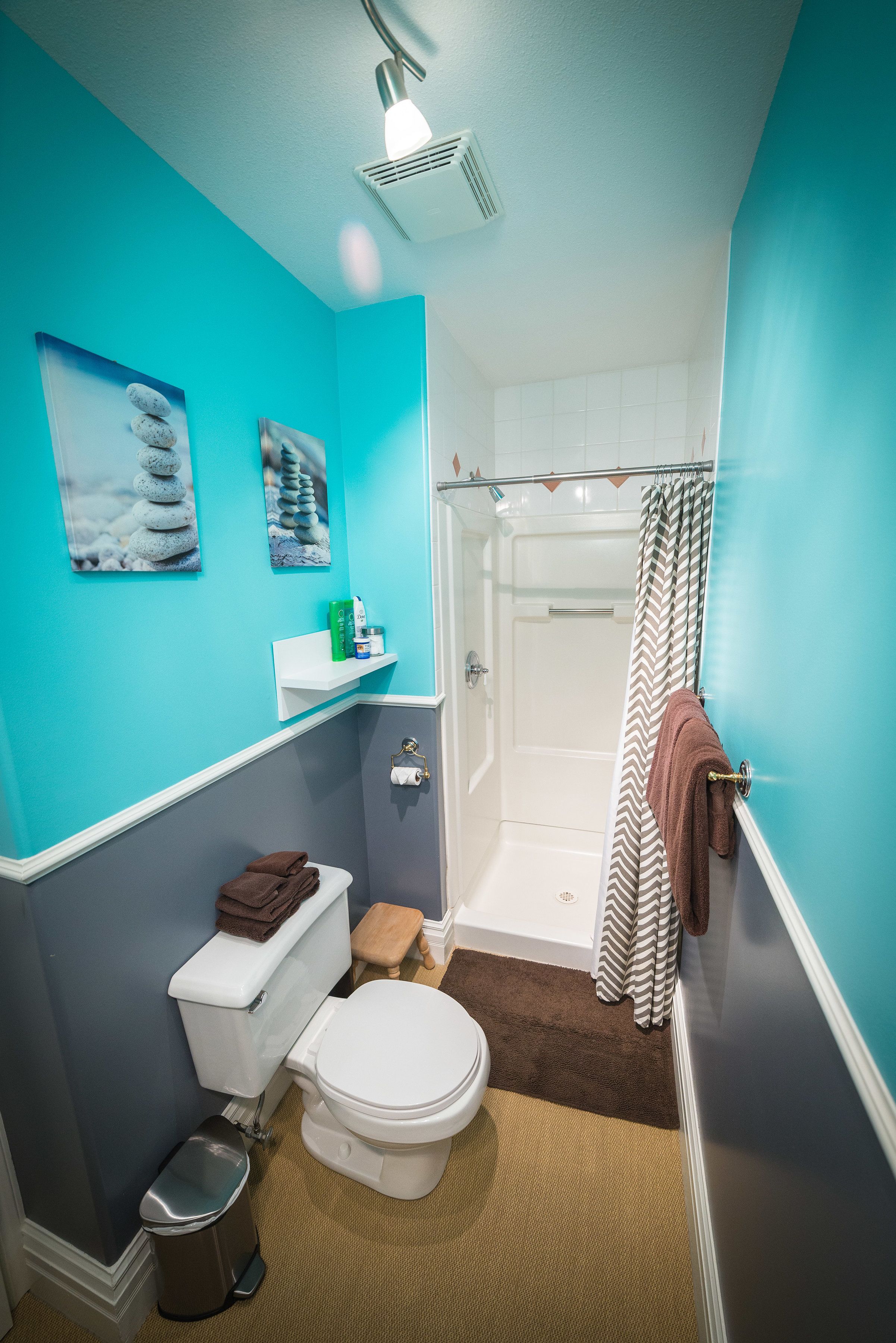 Une salle de bain comprenant des toilettes, un lavabo, une douche et un porte-serviettes.
