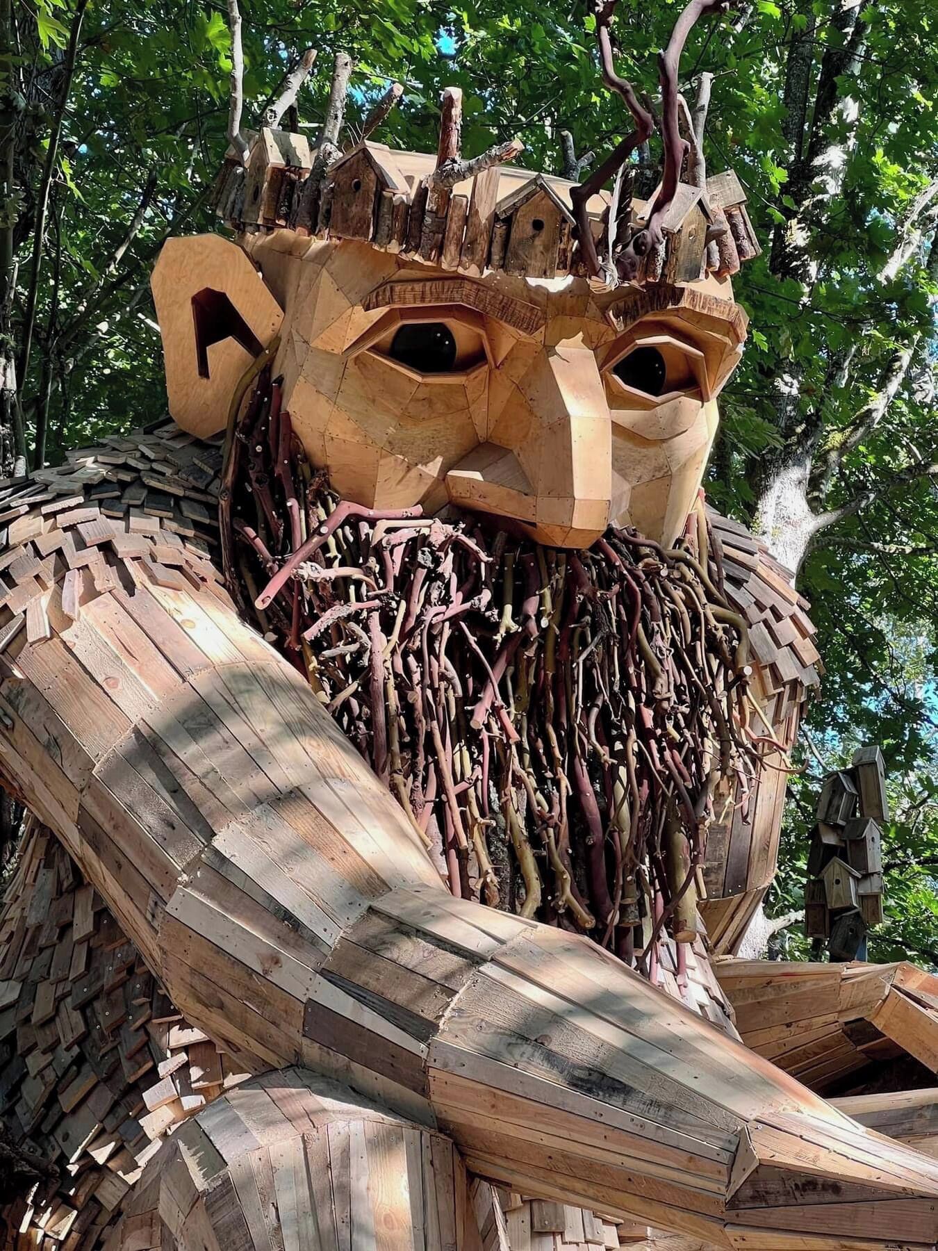 Eine große Holzskulptur, die einen Baum mit einem geschnitzten Gesicht und Ästen darstellt.