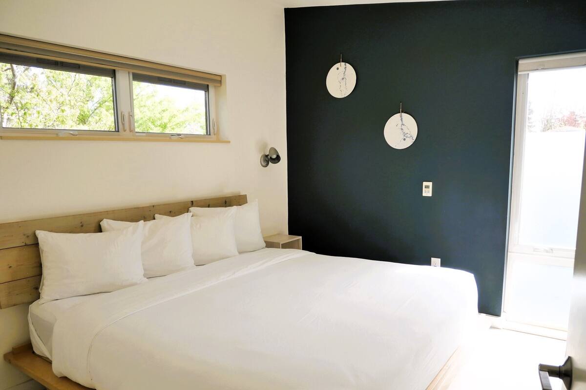 Un dormitorio con una cama grande, una ventana, una pared oscura y dos relojes de pared.
