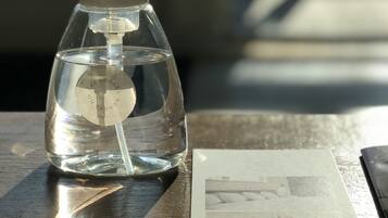 A clear glass bottle with a pump dispenser on a wooden table, next to a printed photograph.