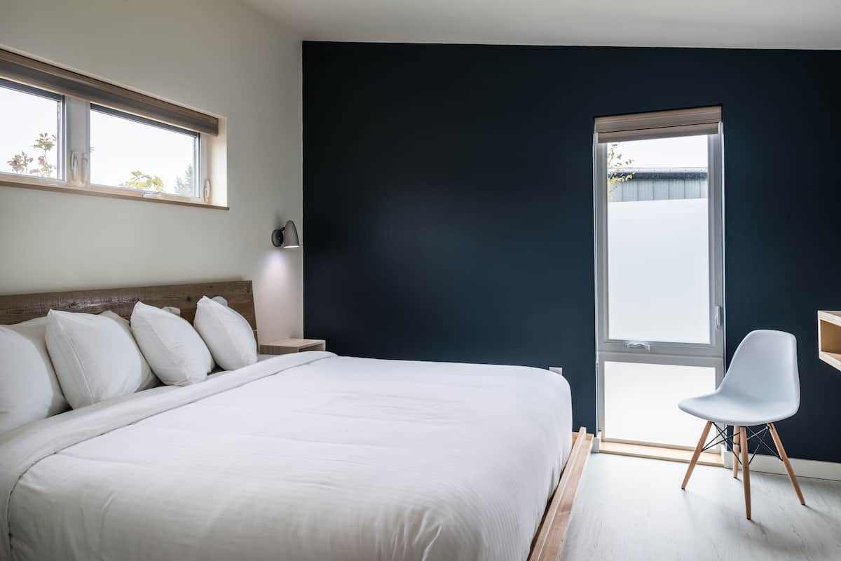 Un dormitorio con una cama grande, una mesita de noche, una silla y una ventana con persianas.
