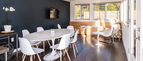A modern dining area with a round table, white chairs, and a dark wooden floor.
