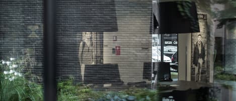 Un bâtiment en briques avec une grande fenêtre qui reflète une personne et une voiture.