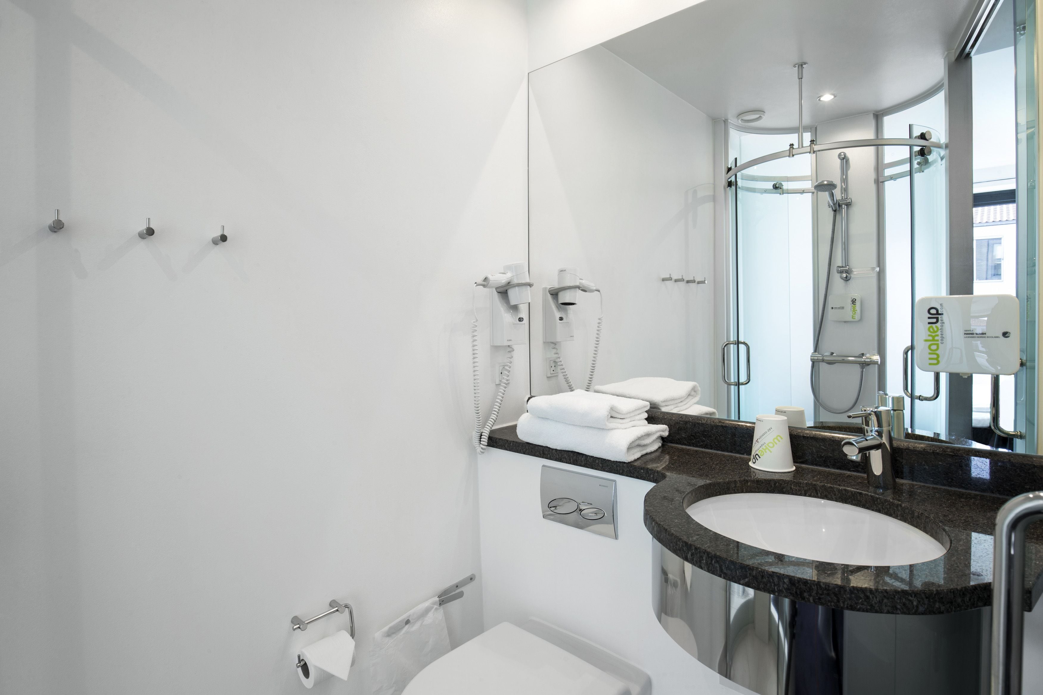 Un baño moderno con un espejo grande, un lavamanos, un inodoro y una ducha.
