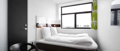 A modern hotel room with a bed, a desk, and a chair.