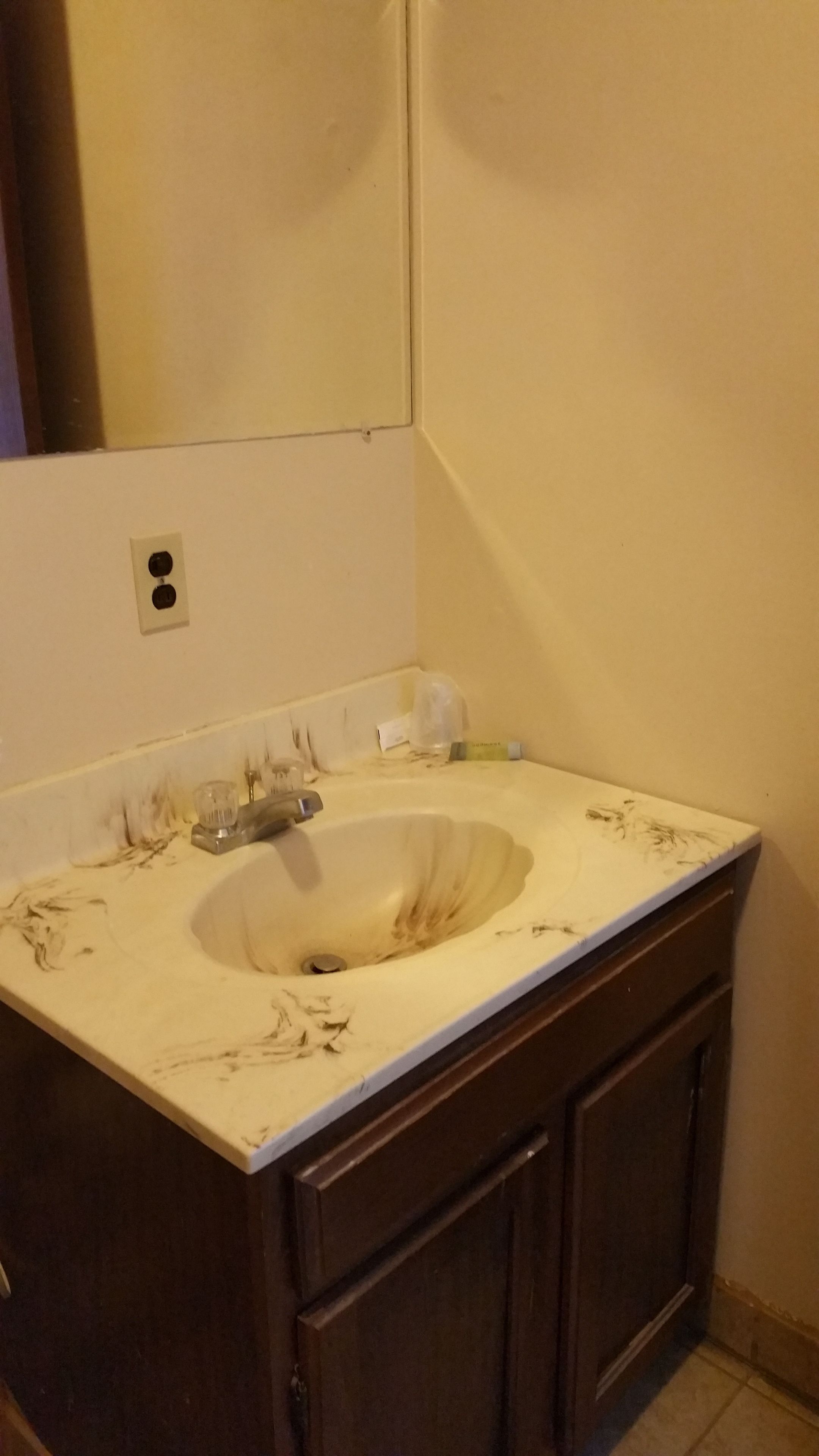 Un baño con lavamanos, espejo y armario.
