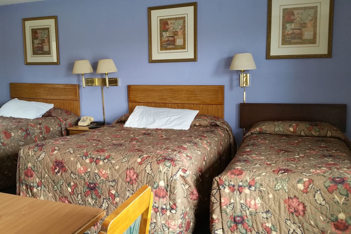 A hotel room with two beds, a wooden table, and two bedside lamps.