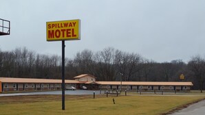 Ein Motel mit einem Schild, auf dem 'SPILLWAY MOTEL' steht, und einem Gebäude mit rotem Dach.