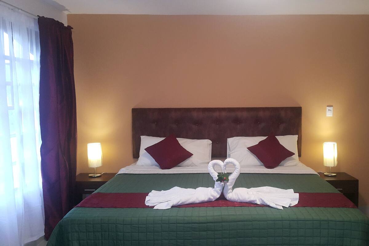 A hotel room with a large bed, two nightstands, and a headboard.