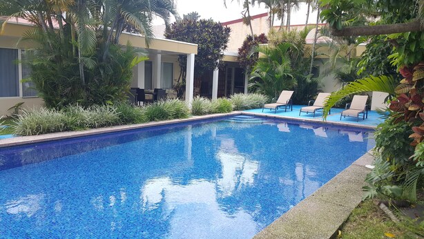 A swimming pool with lounge chairs and tropical plants. - Hotel Portal Colonial (San Rafael)