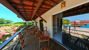 A balcony with wooden chairs and a view of a swimming pool. - Pousada Mar e Brisa (Natal)