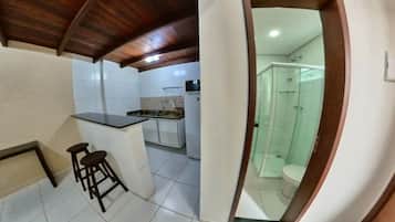 Una cocina con barra, un baño con ducha y un inodoro.